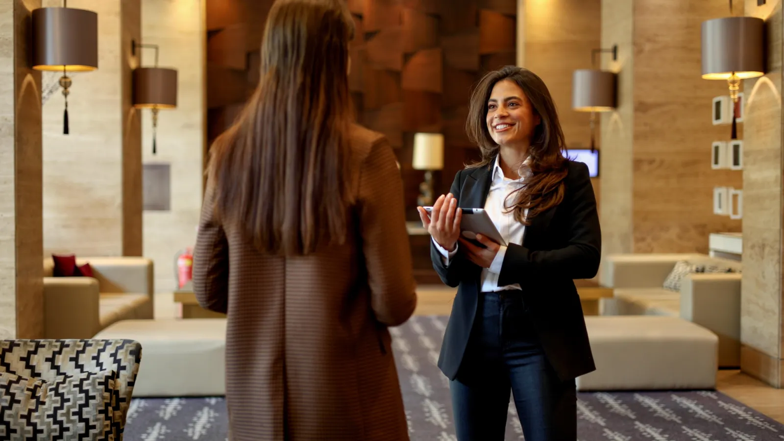 Two people at a hotel reception area, one holding a tablet