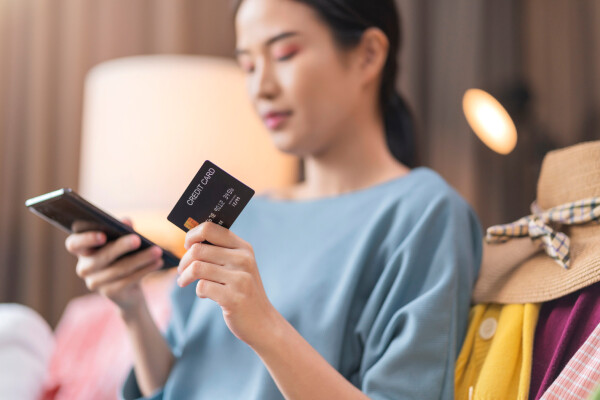 A smiling woman books a hotel stay online using her mobile phone.