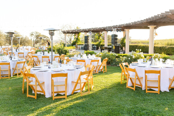 A hotel lawn set with tables and chairs for an early evening event.