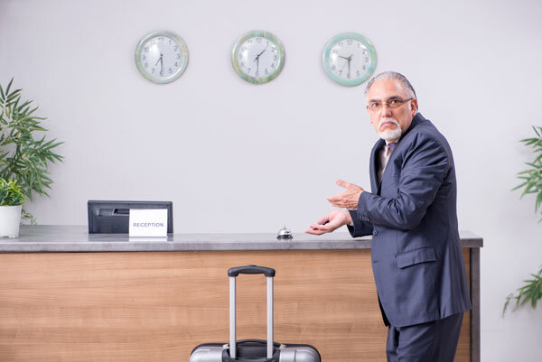 A businessman waits to check in at an abandoned front desk!