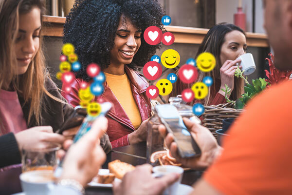 A group of young travelers at a cafe, sharing their experience on social media.