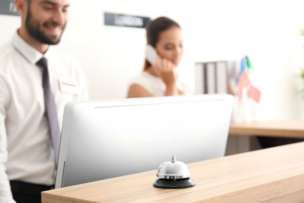 A smiling front desk agent looks up information in the property management system at the front desk computer.