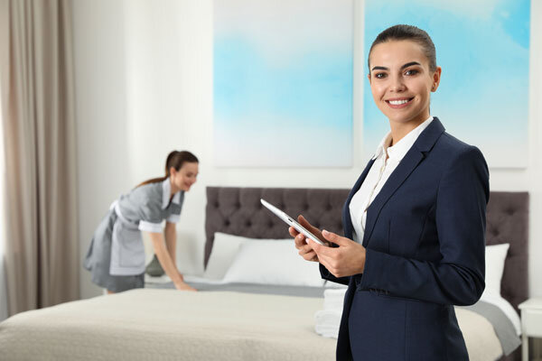 A housekeeping supervisor uses mobile housekeeping software on a tablet device to inspect a room.