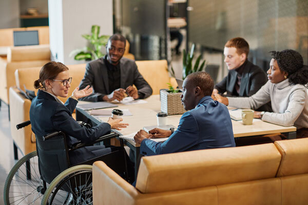 A diverse group of meeting attendees in conversation while seated around a table.