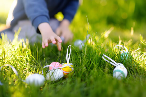 A young boy reaches for Easter eggs in the grass