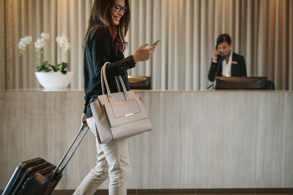 A smiling female business guest skips the front desk using mobile self-check-in.