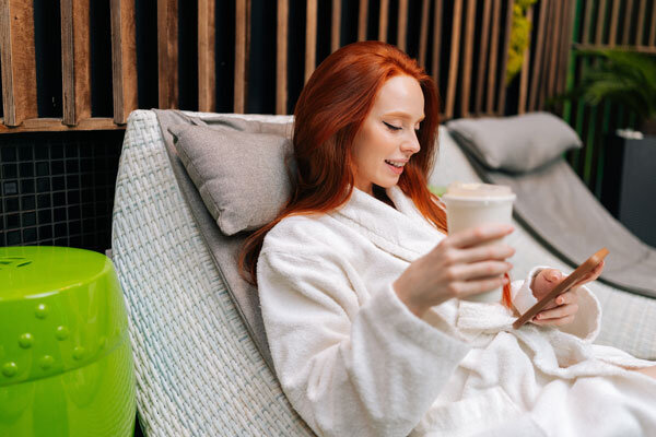 A hotel guest browses hotel amenities on her mobile device while enjoying some time at the hotel spa.