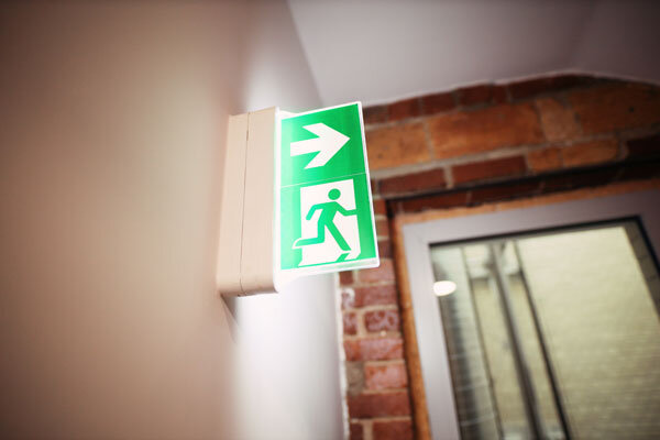 An emergency exit sign lights the way in a hotel corridor.