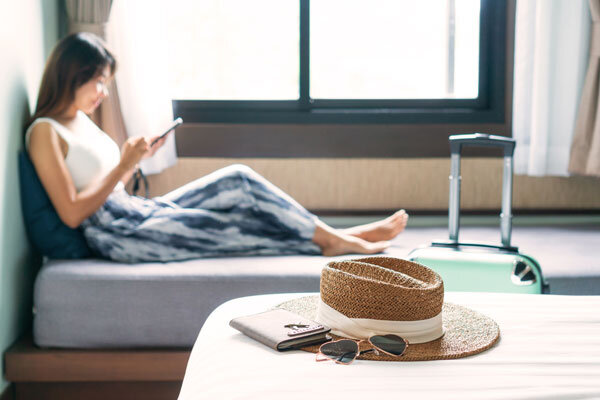 A guest uses a hotel app on her mobile while resting in her hotel room.