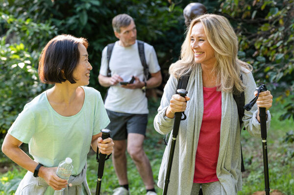 A group of friends from the Baby Boomer generation enjoying a hike in the woods.