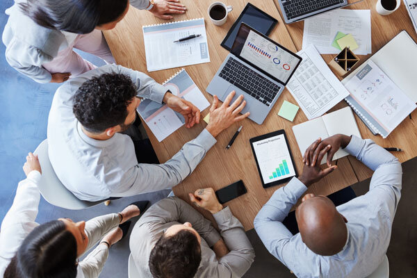 A management team reviewing reports together around a boardroom table.