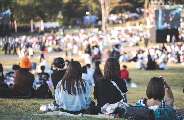 A group of friends sitting on a blanket at an outdoor concert.