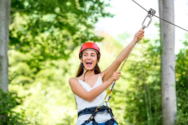 A smiling woman rides a zip line.