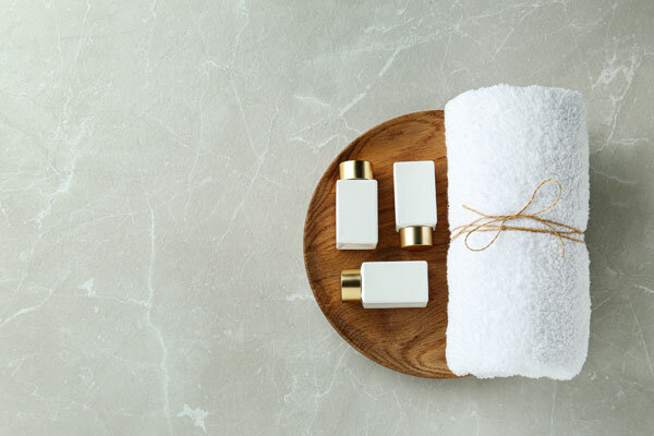 A handtowel and luxury bathroom products carefully placed in a wooden bowl.