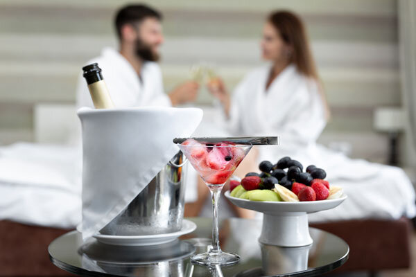 A bottle of champagne on ice and a selection of fresh fruit are enjoyed by honeymooning guests in their hotel room.