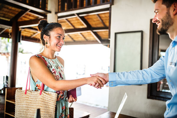 A hotel receptionist warmly greets a guest upon arrival