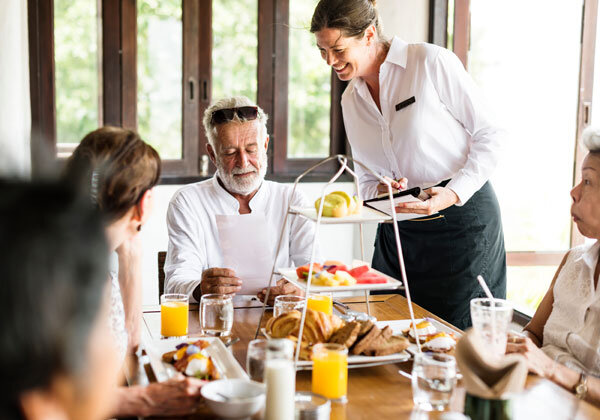 A smiling server takes breakfast orders tableside.