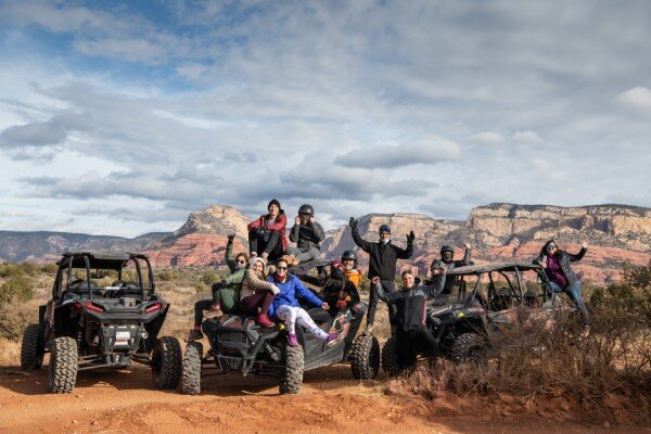 An ATV tour group takes a break in the desert to pose for a photo.