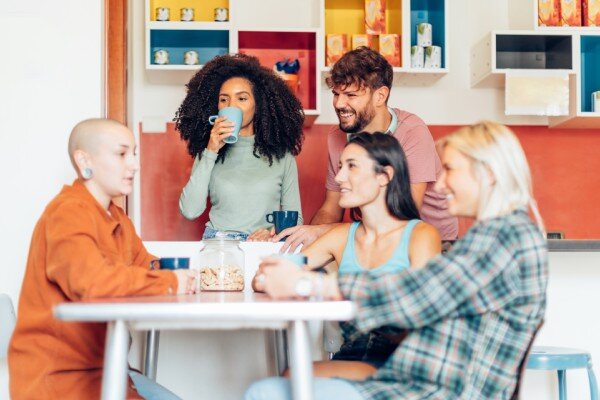 A group of travelers socializing in a trendy hostel kitchen.