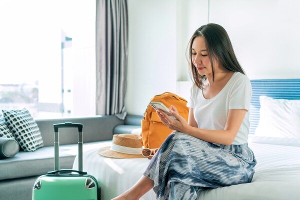 A happy guest asks the front desk a question using mobile messaging from her hotel room.