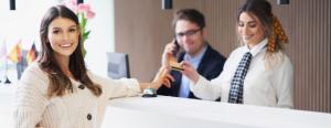 A smiling hotel guest pays at the front desk