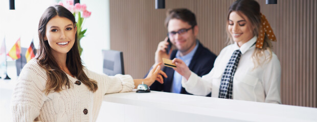 A smiling hotel guest pays at the front desk