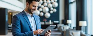 A smiling hotel operator saves time with a cloud PMS on the go in the lobby