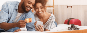A smiling couple book a hotel stay online using their mobile phone