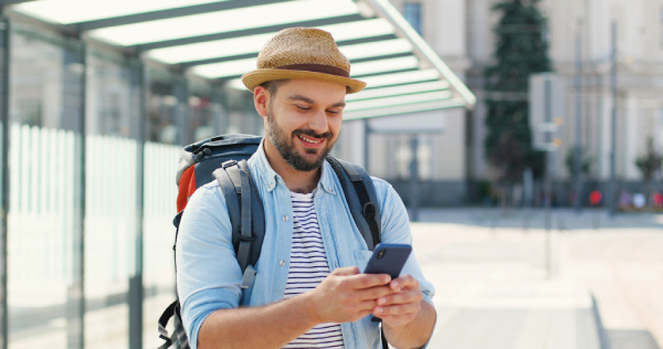 A smiling traveler opens a hotel post-stay email on his phone after checking out.
